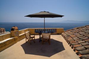 a table and chairs with an umbrella on a balcony at Kissamitakis Guesthouse in Monemvasia