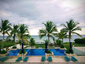 un complejo con una piscina con palmeras y el océano en Disfruta hermosa vista al mar! en San Carlos