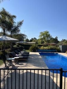 una piscina con sillas y sombrillas junto a una valla en Alexandra Motor Inn - Victoria Aus, en Alexandra