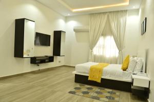 a bedroom with a bed and a tv and a window at ABODE APARTMENTS in Lagos