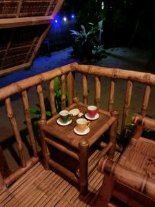 a wooden bench with two cups and saucers on it at Balai Ko Beach & Cottages in El Nido
