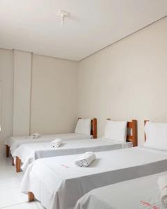 three beds in a white room with white sheets at Lapa Hotel in Bom Jesus da Lapa