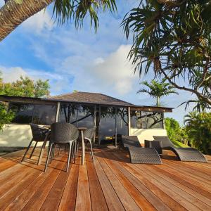 a wooden deck with chairs and a table at Jolie Maison Vue Ocean et Moorea in Punaauia