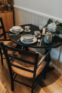 a black dining room table with plates and dishes on it at Wild Orchid Olinda Private Luxury Cottage in Olinda