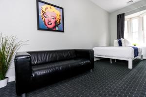 a living room with a black leather couch and a bed at Stylish Studio on Newbury St #3 in Boston