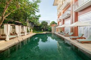 a swimming pool with chairs and umbrellas next to a building at Maison Aurelia Sanur, Bali - By Pr&eacute;f&eacute;rence in Sanur