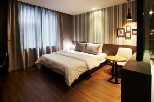 um quarto com uma cama, uma mesa e uma janela em Brown Dot Hotel GimhaeEobang em Gimhae