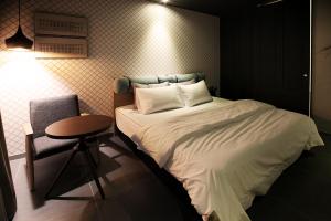 um quarto com uma cama, uma cadeira e uma mesa em Brown Dot Hotel GimhaeEobang em Gimhae