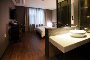 um quarto de hotel com um lavatório e uma cama em Brown Dot Hotel GimhaeEobang em Gimhae