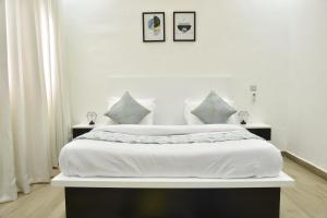 a white bedroom with a large white bed with pillows at ABODE APARTMENTS in Lagos