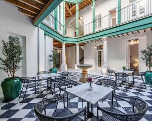 - un patio avec des tables et des chaises sur un sol en damier dans l'établissement Palacio Vegafuente by Caleta Homes, à Malaga