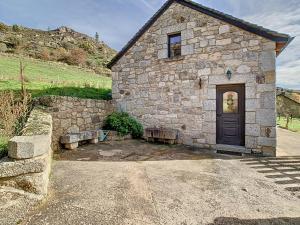 un edificio de piedra con una puerta y un banco en Gîte authentique -Mont Lozère en Les Bondons