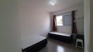 a small room with two beds and a window at AP Bertioga - Praia Indaia - Wi-Fi 500 Mega in Bertioga