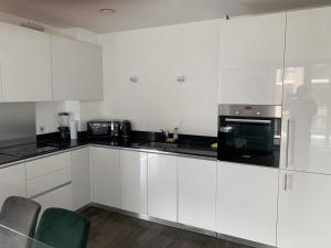 a white kitchen with white cabinets and a microwave at 2 bedroom 2 bath 1 ensuite in Roya Asenal beautiful views & parking in Woolwich