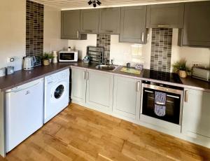 cocina con electrodomésticos blancos y suelo de madera en Oak Lodge 7 Hot Tub, en York