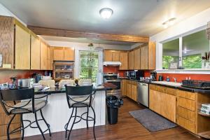 a kitchen with wooden cabinets and a counter with stools at Mountain Meadows Inn & Chalet Suites in Ashford