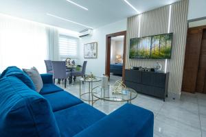 a living room with a blue couch and a dining room at Soha Suites Santiago Gem Rare Find in Santiago de los Caballeros