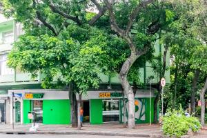 um edifício verde com árvores em frente em Quarto próximo da Savassi. em Belo Horizonte