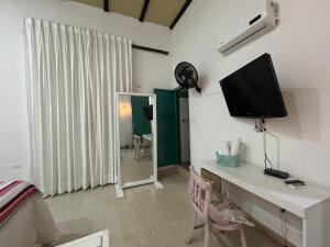 a bedroom with a desk with a television on a wall at Hotel La Casa Ovalle in San Vicente de Chucurí