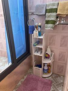 a bathroom with a shower with towels and a shelf at Chez nous in Madina