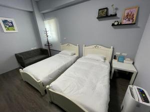 2 łóżka pojedyncze w pokoju z telewizorem w obiekcie SummerMallika 夏茉民宿 w mieście Magong
