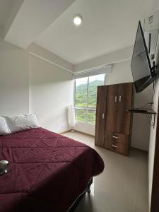 聖赫羅尼莫的住宿－Edén de Alejo - Apartamento - Lujo y Confort en San Jerónimo，一间卧室设有一张床、一台电视和一个窗口。