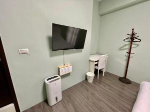 Habitación con TV en la pared y escritorio. en SummerMallika 夏茉民宿, en Magong