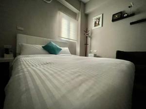 ein Schlafzimmer mit einem großen weißen Bett mit einem blauen Kissen in der Unterkunft SummerMallika 夏茉民宿 in Magong