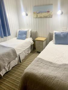 a room with two beds and a nightstand between them at Maple Lodge 11 Hot Tub & Sauna in York