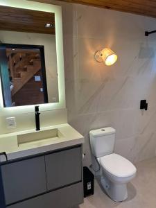 a bathroom with a toilet and a sink and a mirror at Refúgio vila das figueiras ! in Torres +18 photos