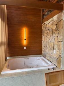 uma banheira num quarto com uma parede de pedra em Refúgio vila das figueiras ! em Torres