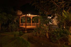 einen hölzernen Pavillon in einem Garten in der Nacht in der Unterkunft FAREL HOMESTAY KAWAHIJEN in Banyuwangi