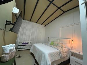 1 dormitorio con 1 cama y TV. en Hotel La Casa Ovalle en San Vicente de Chucurí