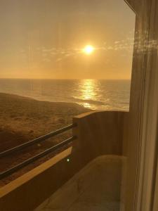 a view of the ocean from a window with the sunset at Mirleft Seaside Horizon in Mirleft