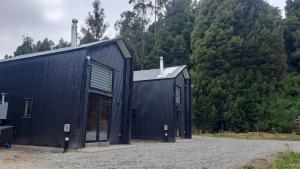 a black building with trees in the background at Cabaña Valdivia Piedra Blanca 2 in Valdivia