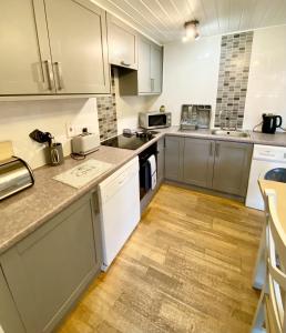 a large kitchen with white cabinets and wooden floors at Beech Lodge 5 Hot Tub in York