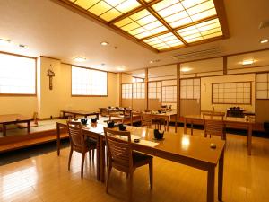 una grande stanza con tavoli, sedie e finestre di 水と緑のやすらぎの宿　一の瀬 a Mishima