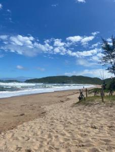 a sandy beach with people walking on the beach at Cabana Bela Vista in Búzios