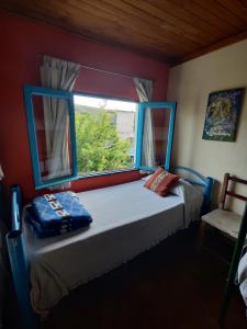 1 dormitorio con 1 cama con ventana y silla en Onda Verde Hostal in 