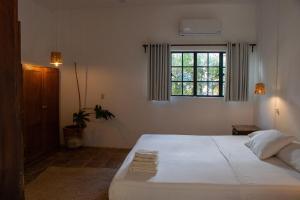 a bedroom with a white bed and a window at Soiree in Zipolite
