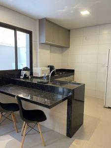 a kitchen with a black counter and two chairs at Espaço aconchegante com wifi! in Patos de Minas