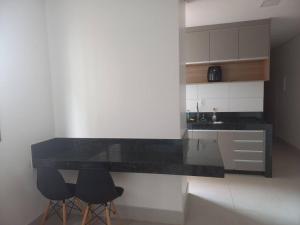 a kitchen with a black counter and two stools at Espaço aconchegante com wifi! in Patos de Minas