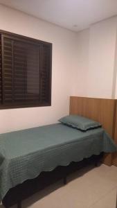 a bed in a room with a window at Espaço aconchegante com wifi! in Patos de Minas