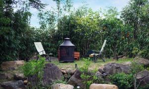 a garden with a lantern and chairs and trees at Aurora Hotel in Jeju