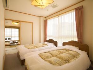 una camera da letto con due letti e una finestra di 水と緑のやすらぎの宿　一の瀬 a Mishima