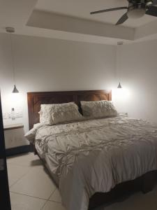 um quarto com uma cama grande com lençóis brancos e almofadas em Bay View Grand Marina Ixtapa condo en pie de playa em Ixtapa