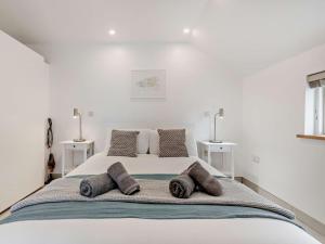 a white bedroom with a large bed with three pillows at 1 Bed in Totnes 93061 in Marldon