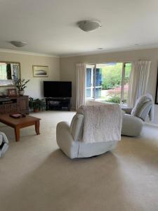 ein Wohnzimmer mit 2 weißen Stühlen und einem TV in der Unterkunft Spacious Home in Paraparaumu