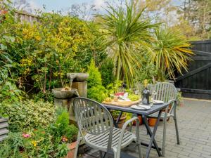1 Bed in Highcliffe 90444 في هايكليف: طاولة وكراسي في حديقة بها نباتات