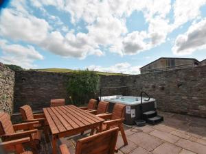 un patio con tavolo, sedie e vasca idromassaggio di 5 Bed in Brecon 90660 a Lower Chapel